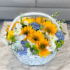 Basket of sunflowers, blue hydrangeas, and white flowers with a butterfly decoration