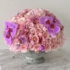 Pink rose and orchid arrangement in a stone pedestal vase