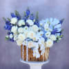 White roses and orchids arranged with blue flowers in a woven basket