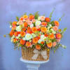 Basket arrangement of orange, pink, and white roses with a ribbon bow