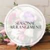 Round bouquet with pink, white, and lavender flowers wrapped in clear paper