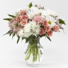 Pink roses and white daisies arranged in a clear glass vase