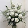 White roses arranged in a clear glass vase with airy greenery