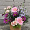 Soft pink gerbera daisies and pale blush roses mingle with vivid purple