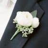 White boutonniere with small greenery on a dark suit lapel