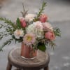 Pink and white bouquet in a copper vase on a stool