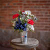 Bouquet of red and white flowers in a silver cup with a blue ribbon
