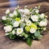 White floral arrangement with a small angel figurine in the center