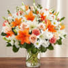 Orange lilies and peach roses in a clear glass vase