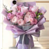 Bouquet of pink and lavender roses wrapped in purple paper