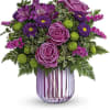 Purple roses and mixed purple flowers in a pink glass vase