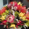 Colorful bouquet with protea, pink blooms, and yellow petals in a vase