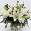 White lilies and roses arranged in a clear glass vase