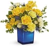 Yellow and white flower arrangement in a blue glass vase