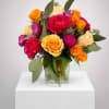 Mixed bouquet of orange and pink flowers in a glass vase
