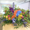Large colorful floral arrangement with roses, hydrangeas, and purple blooms on a table