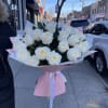 Large bouquet of white roses wrapped in pink paper with ribbon