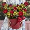 Red roses and yellow orchids arranged in a round red box with a ribbon