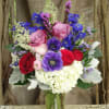 Mixed bouquet of roses, anemones, and hydrangea in a glass vase