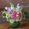 Pink and white flower arrangement in a green glass vase