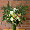 Tall floral arrangement with white roses and orchids in a green vase