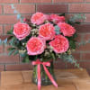 Pink roses in a glass vase with eucalyptus and a pink ribbon