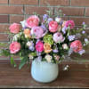 Pink and lavender flower arrangement in a pale blue vase