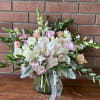 Pink and white bouquet in a glass vase with trailing greenery