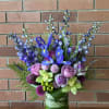 Blue iris and purple flowers in a green glass vase