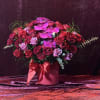 Pink and red rose arrangement with orchids in a round box tied with a ribbon