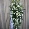 Tall white floral standing spray with ribbon on an easel