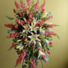 Tall floral spray with white lilies, pink blooms, and blue accents on a stand