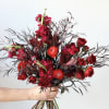 Handheld bouquet of red roses and dark foliage
