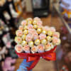 Pink roses and gold-wrapped chocolates in a red heart-shaped box with a ribbon