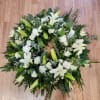 White floral wreath with lilies and roses on a wooden floor