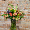 Mixed bouquet in a glass vase with coral, peach, purple, and white blooms