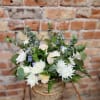White floral arrangement in a woven basket with eucalyptus
