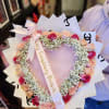 Heart-shaped bouquet of pink and peach roses with white baby's breath