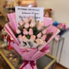 Bouquet of pale pink roses wrapped in pink paper with a ribbon