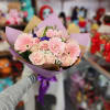 Bouquet of pink gerbera daisies and roses wrapped in purple paper