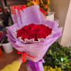 Bouquet of red roses wrapped in lavender paper with red ribbons