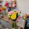 Bouquet of yellow roses and pink gerbera daisies in a glass vase