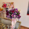 Purple and pink mixed bouquet in a white cup with a pink ribbon