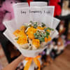 Bouquet of yellow roses wrapped in white paper with an orange ribbon