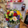 Mixed bouquet of roses, carnations, and purple filler in a glass vase