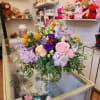 Mixed bouquet of pink, purple, and peach flowers in a glass vase