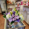 Basket arrangement of lilies, chrysanthemums, and hydrangeas in purple and white