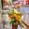 Bouquet of yellow, orange, and white flowers in a textured amber vase