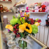 Bouquet of yellow roses, sunflowers, and green chrysanthemums in a glass vase