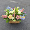 Basket of mixed pastel flowers with roses and blue blooms